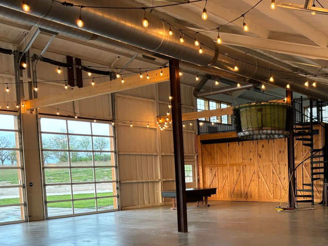 The empty main floor with polished concrete, string lights, barn doors and the spiral staircase